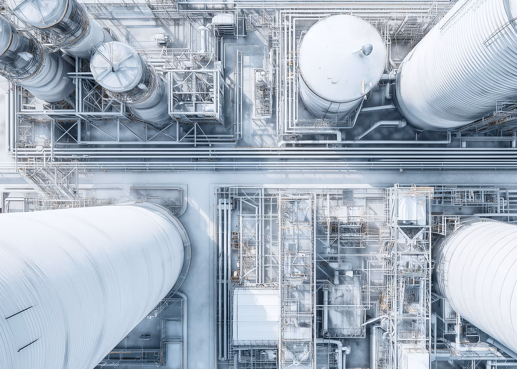 Aerial view of an industrial facility with large cylindrical storage tanks and complex piping network.