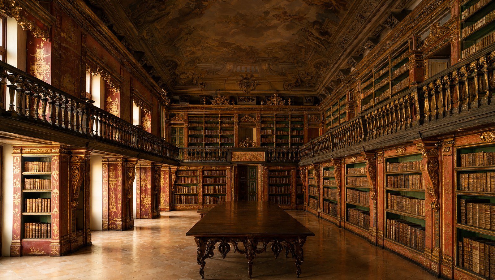 Intérieur baroque de la Biblioteca Joanina, rayonnages dorés sur deux niveaux