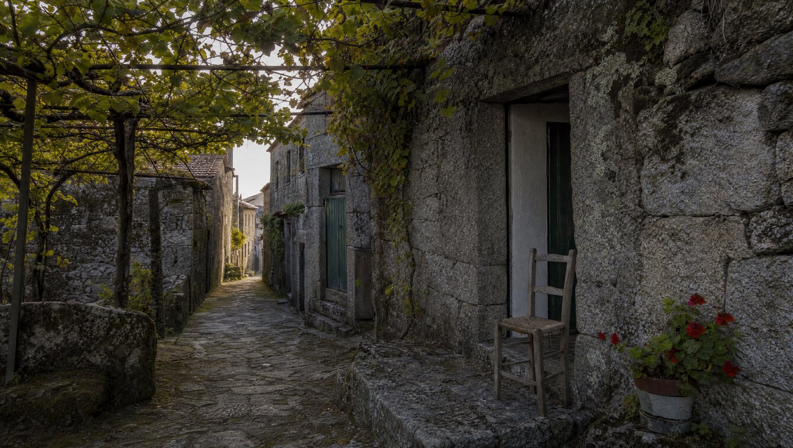 Ruelle de granit et chaise vide devant une porte, village du Minho