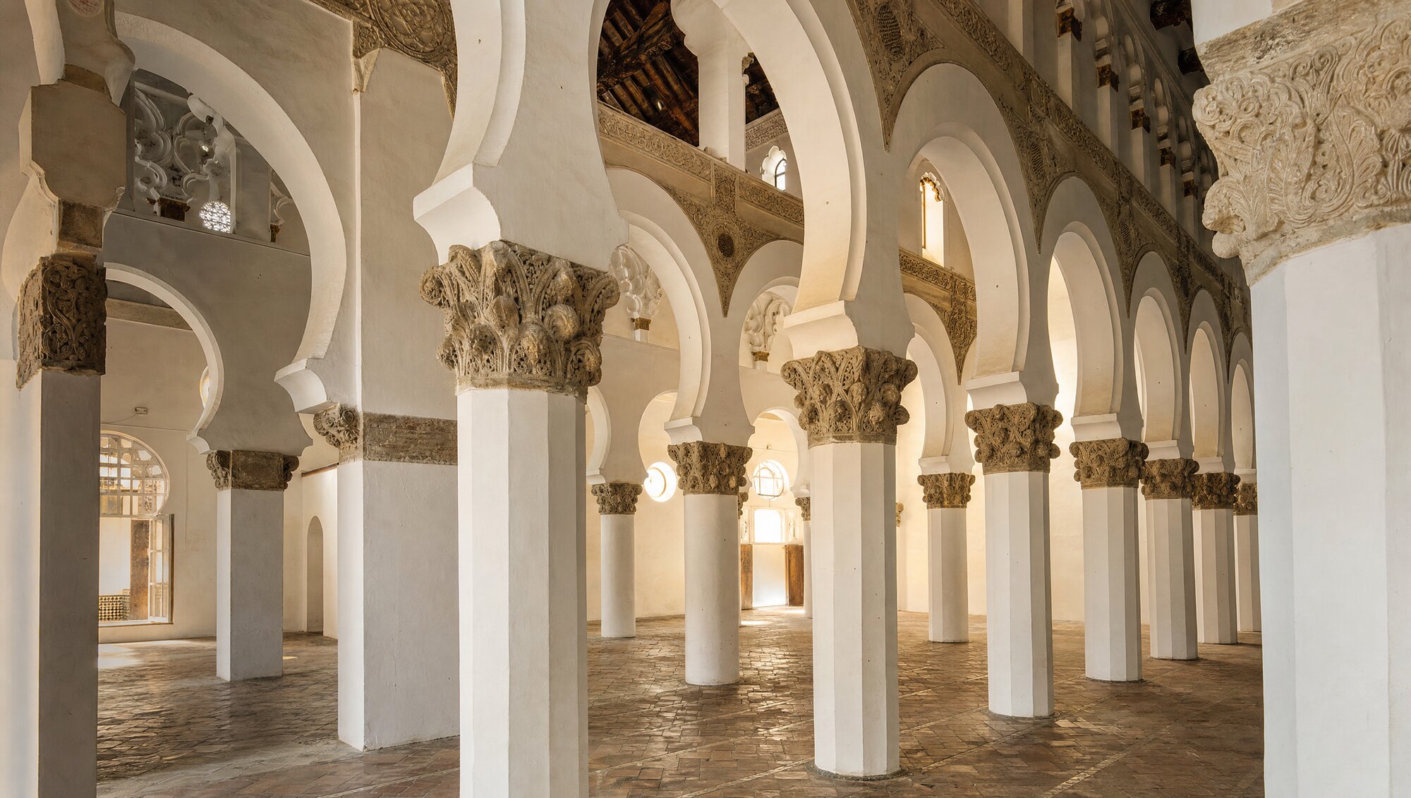 Forêt de piliers blancs et d'arcs en fer à cheval de style mudéjar dans une synagogue de Tolède