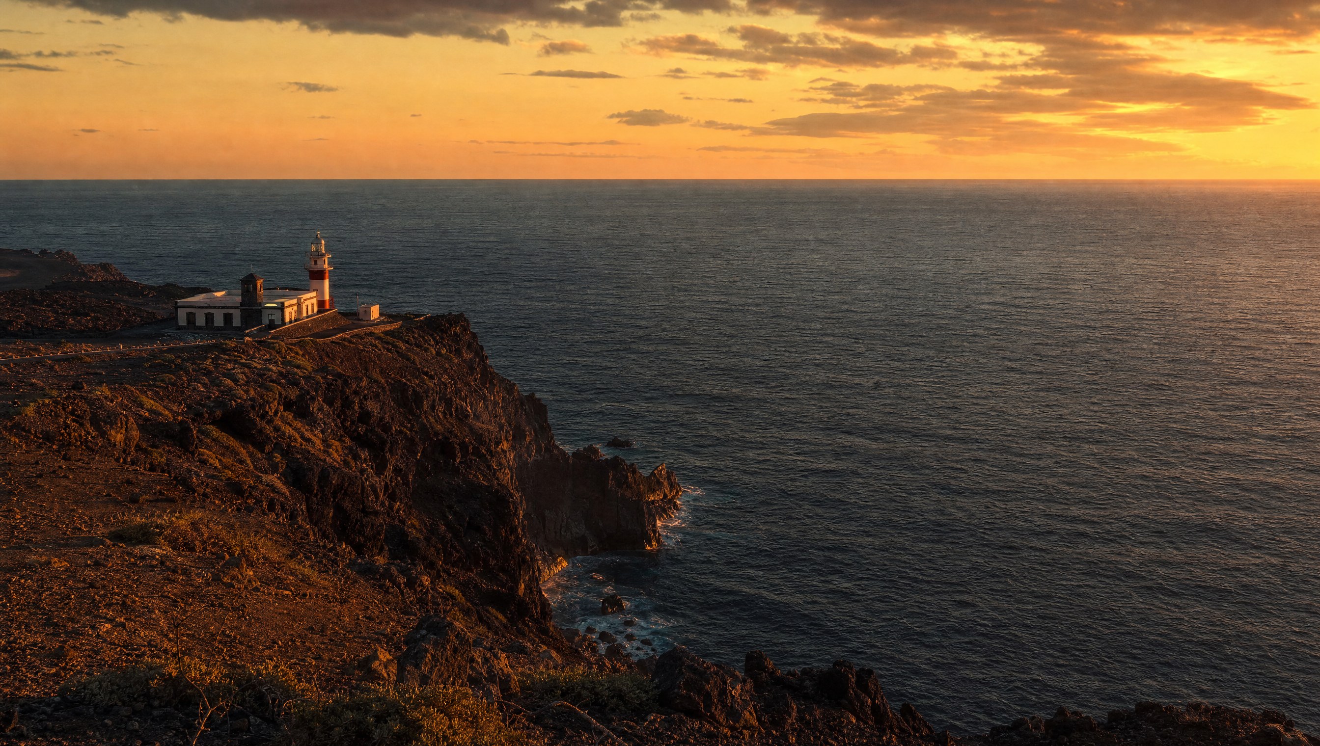 La Punta de Orchilla, pointe rocheuse volcanique à l'extrême ouest d'El Hierro plongeant dans l'Atlantique, phare isolé, lumière de fin de jour sur l'océan ouvert