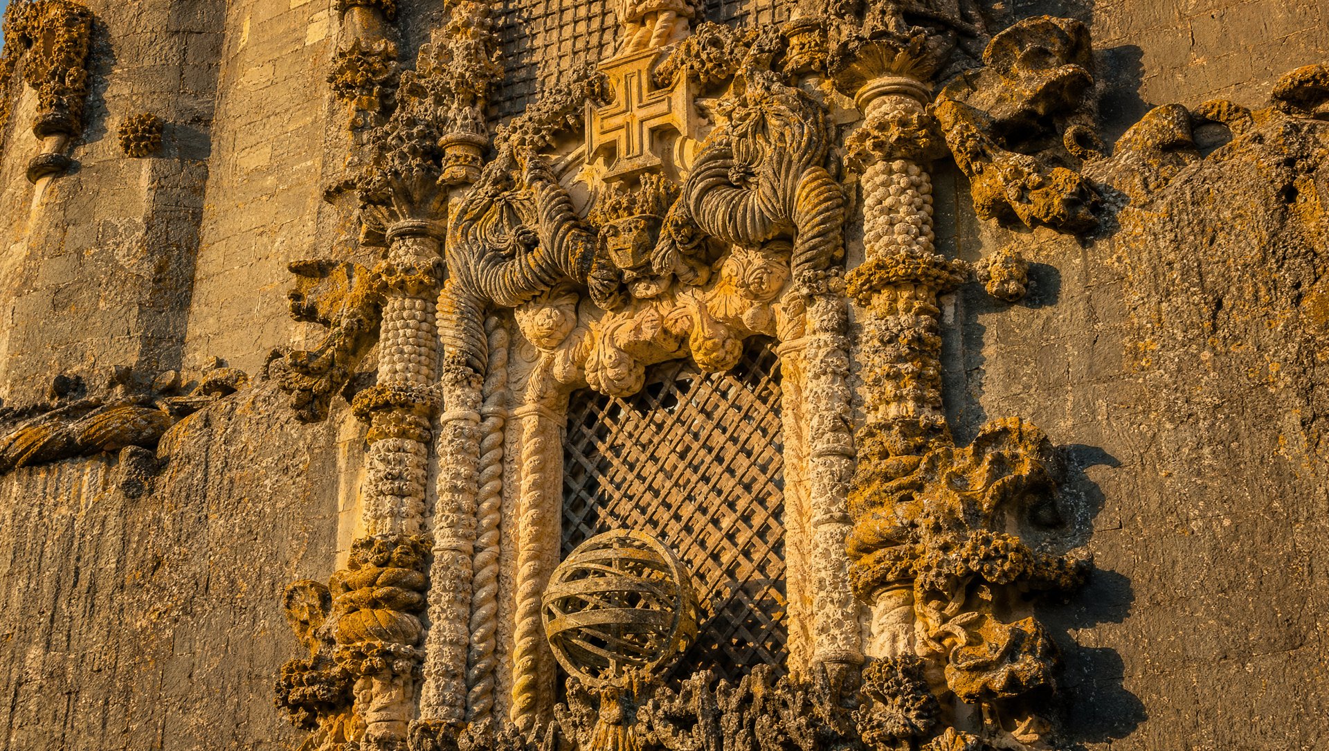La Janela do Capítulo (fenêtre du Chapitre) du Convento de Cristo de Tomar, chef-d'œuvre de l'art manuélin, cordages, corail et racines de liège sculptés dans le granit, sphère armillaire et croix de l'Ordre du Christ, lumière dorée de fin d'après-midi