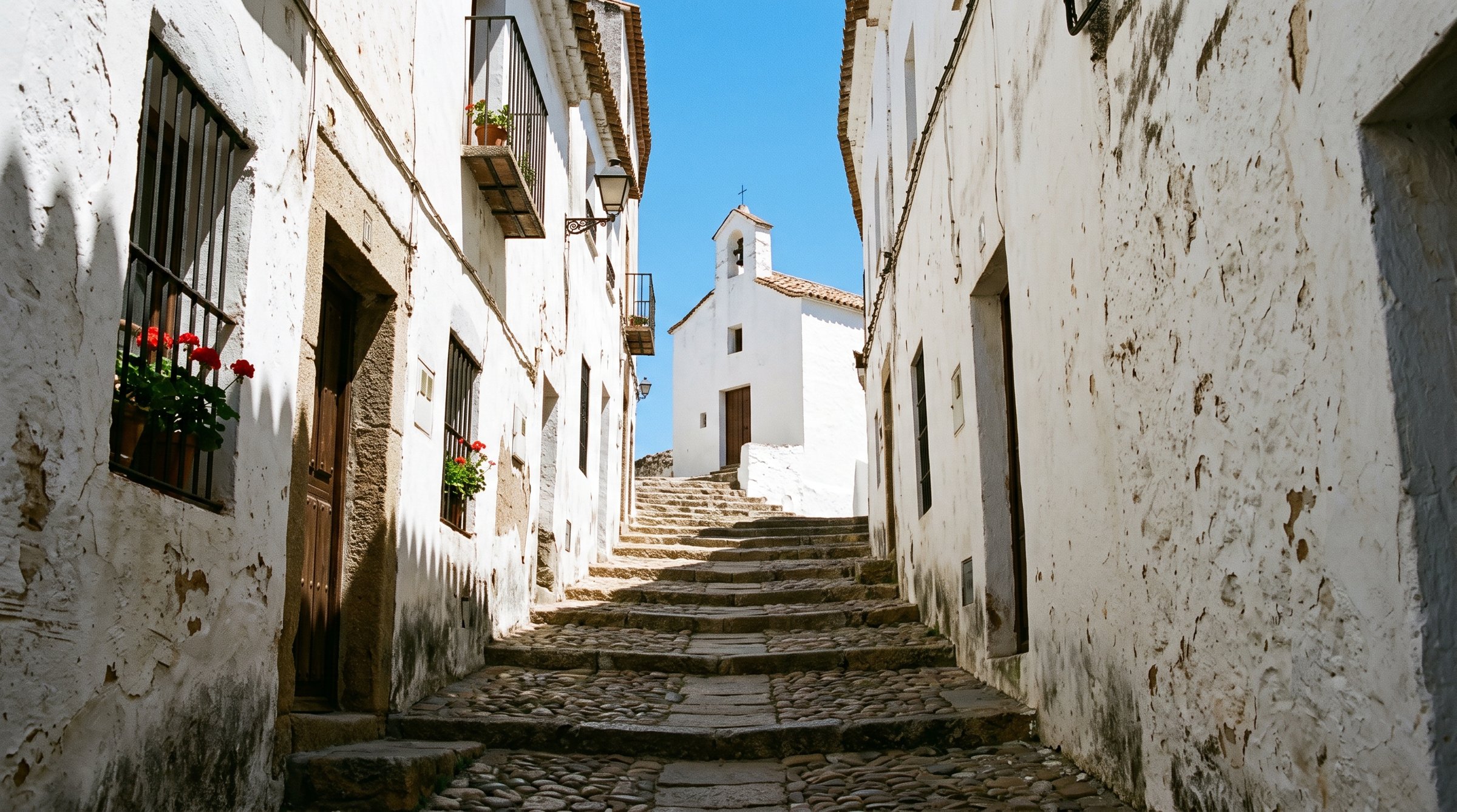 Ruelle étroite et blanchie à la chaux de la Judería Vieja de Cáceres montant en escalier vers l