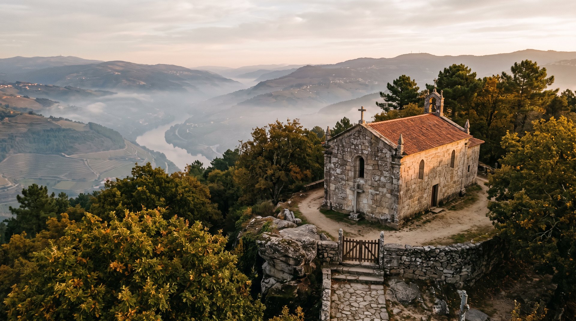 Ermitage de granit médiéval isolé au sommet d'une colline boisée au-dessus de Lamego, lumière rasante de fin d'après-midi, brume légère sur la vallée du Douro, ambiance de vieux Portugal dévotionnel