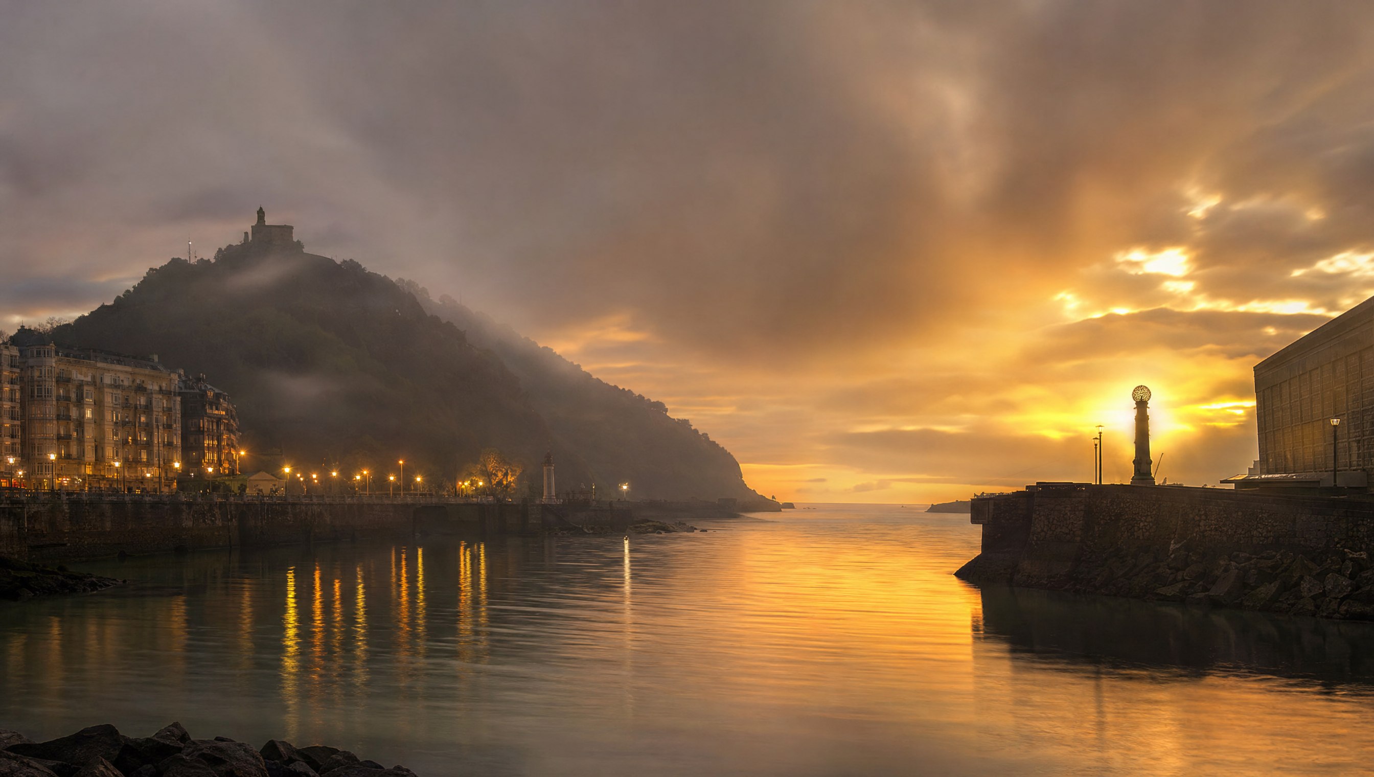 L’embouchure du fleuve Urumea à Saint-Sébastien au crépuscule, eaux calmes de l’estuaire, reflets dorés et brume légère, ambiance mystérieuse et mythologique, aucune personne, Pays basque