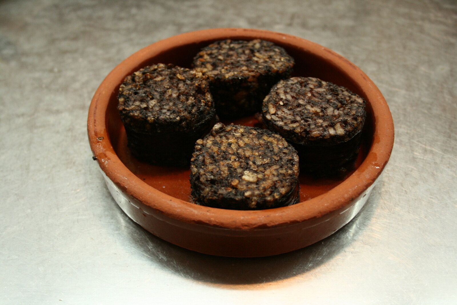Table castillane rustique de Burgos avec olla podrida fumante dans une marmite en terre, morcilla de Burgos grillée, verre de vin rouge Ribera del Duero et fromage frais de Burgos au miel, lumière chaude, style photographie culinaire réaliste