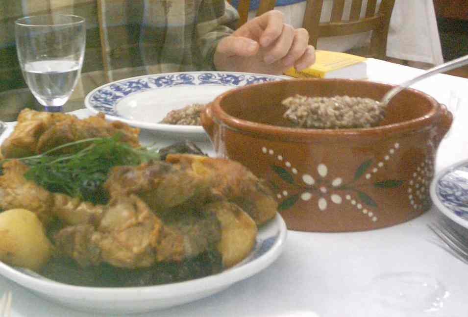 Arroz de sarrabulho à moda de Ponte de Lima et rojões, le plat traditionnel du Minho servi dans un plat en terre cuite, sur une table de restaurant