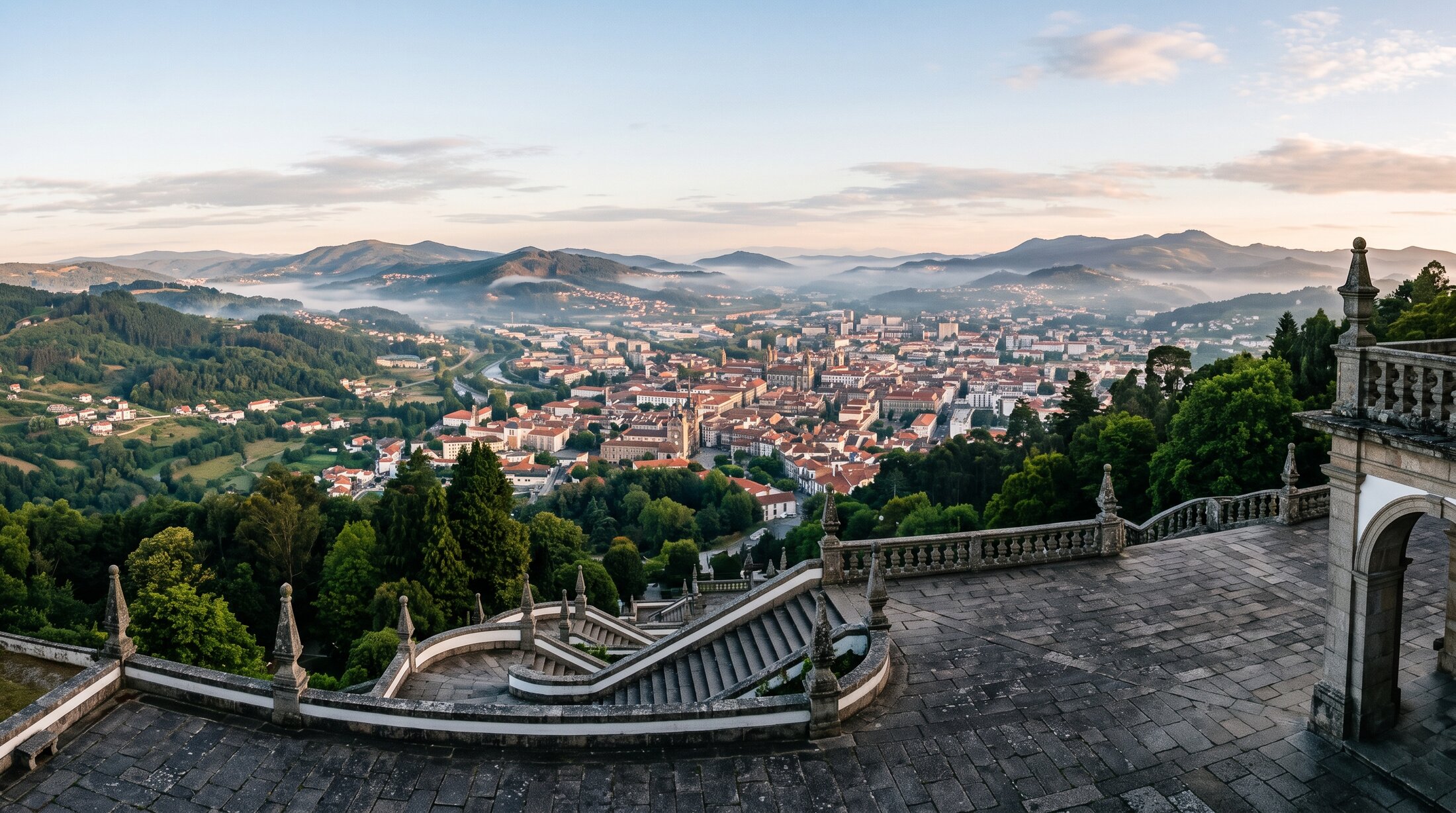 Vue panoramique depuis le parvis du Bom Jesus do Monte sur la ville de Braga et le Minho verdoyant en contrebas, collines boisées et brume légère du matin, Portugal