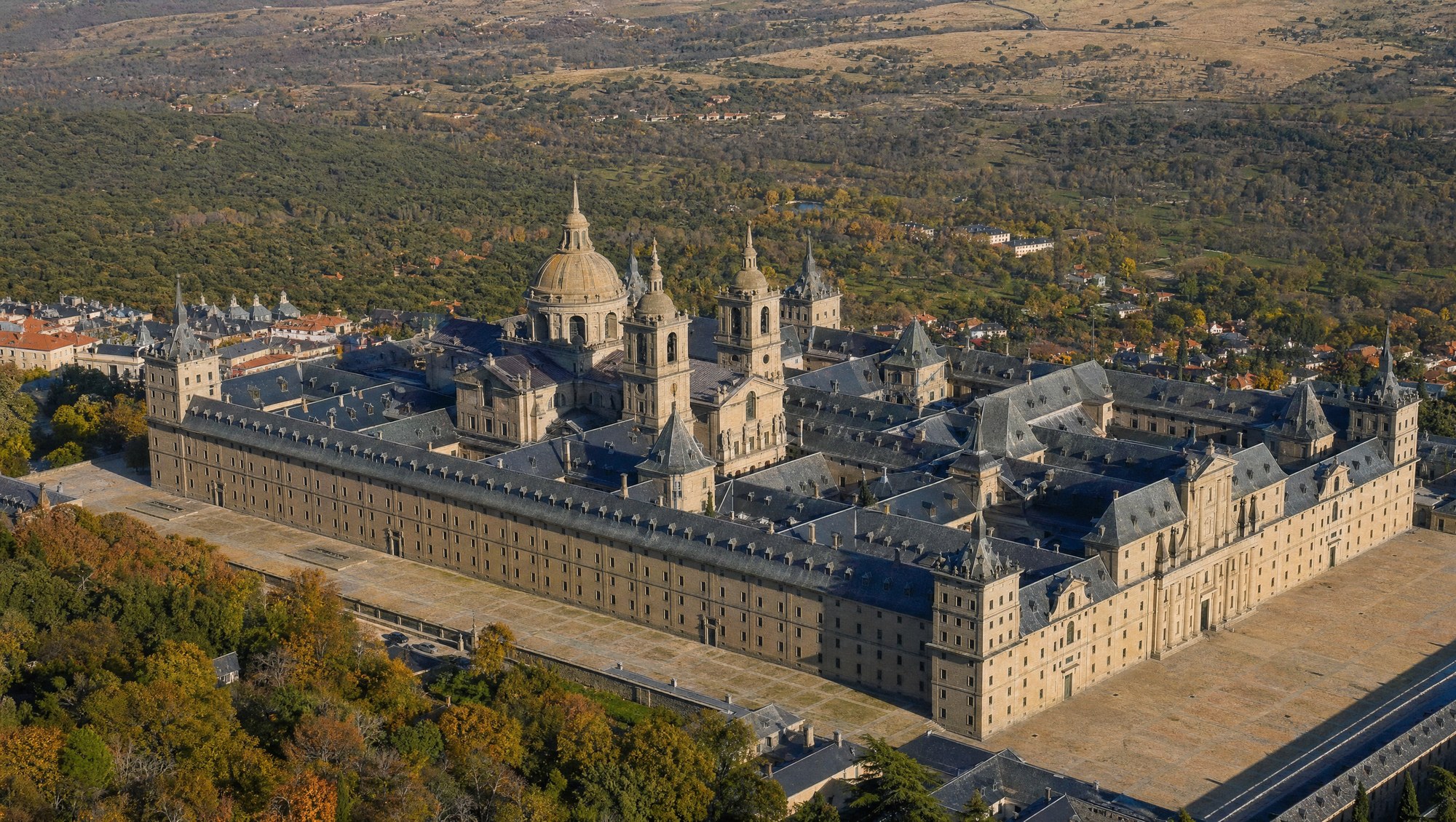 Vue aérienne du monastère de l'Escorial montrant le plan quadrillé en forme de gril, cours intérieures et galeries de granit gris sous un ciel d'automne
