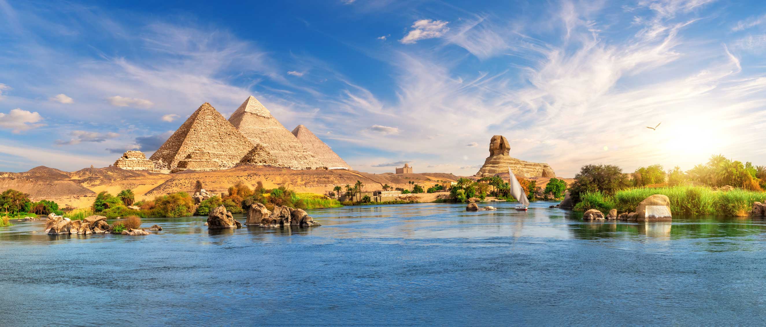 Egypt's Giza Plateau with pyramids and sphinx in the background and Nile river in the foreground