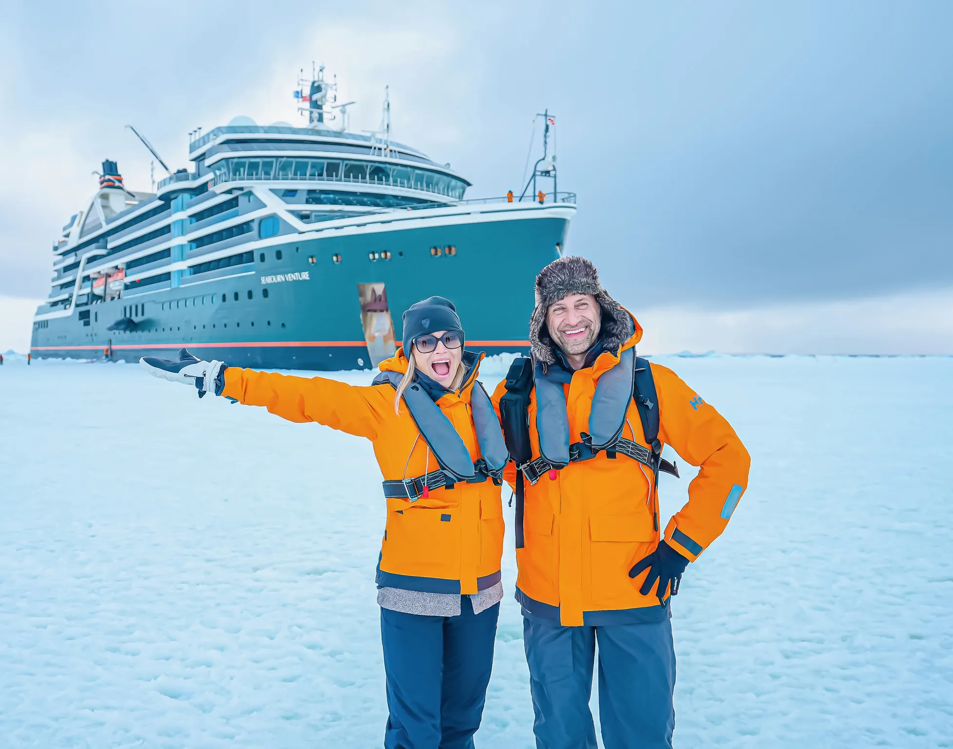 Phil and Erin Lockwood standing on Antarctic ice with a cruise ship in the background