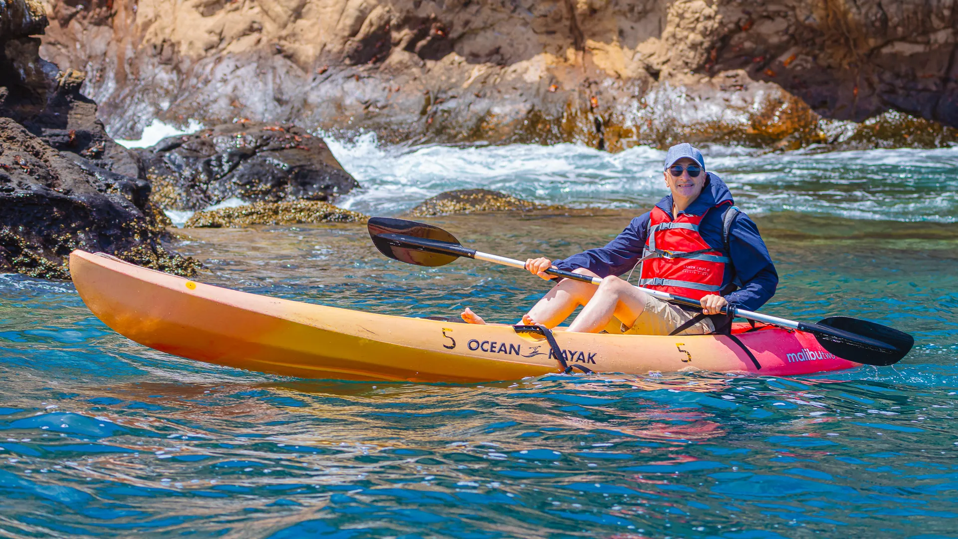 A kayaker coasts past a rocky shore in the Galapagos