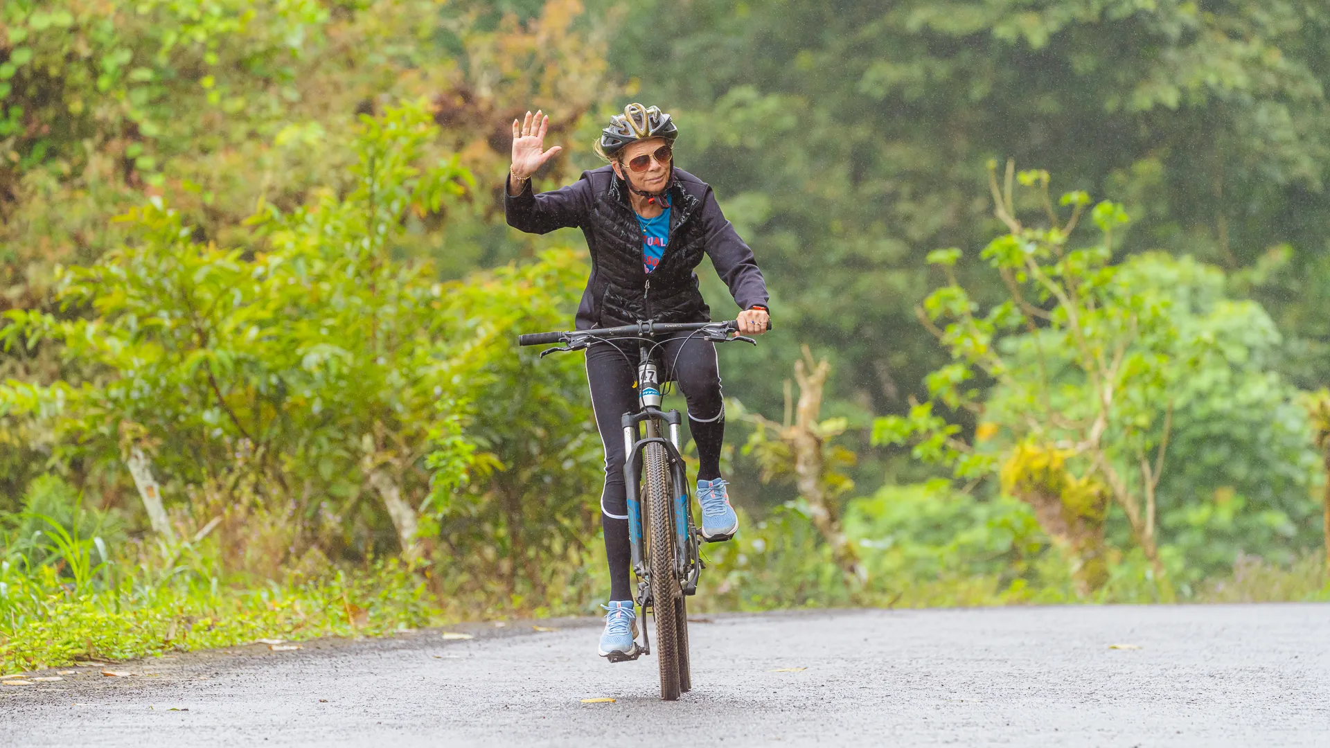 Mary Elbe rides a bike along a dirt road in the Galapagos Islands