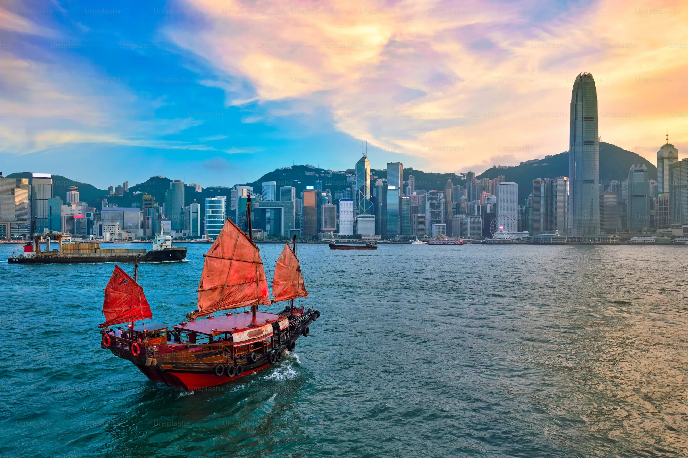 An authentic sailboat sails toward the skyline of Hong Kong