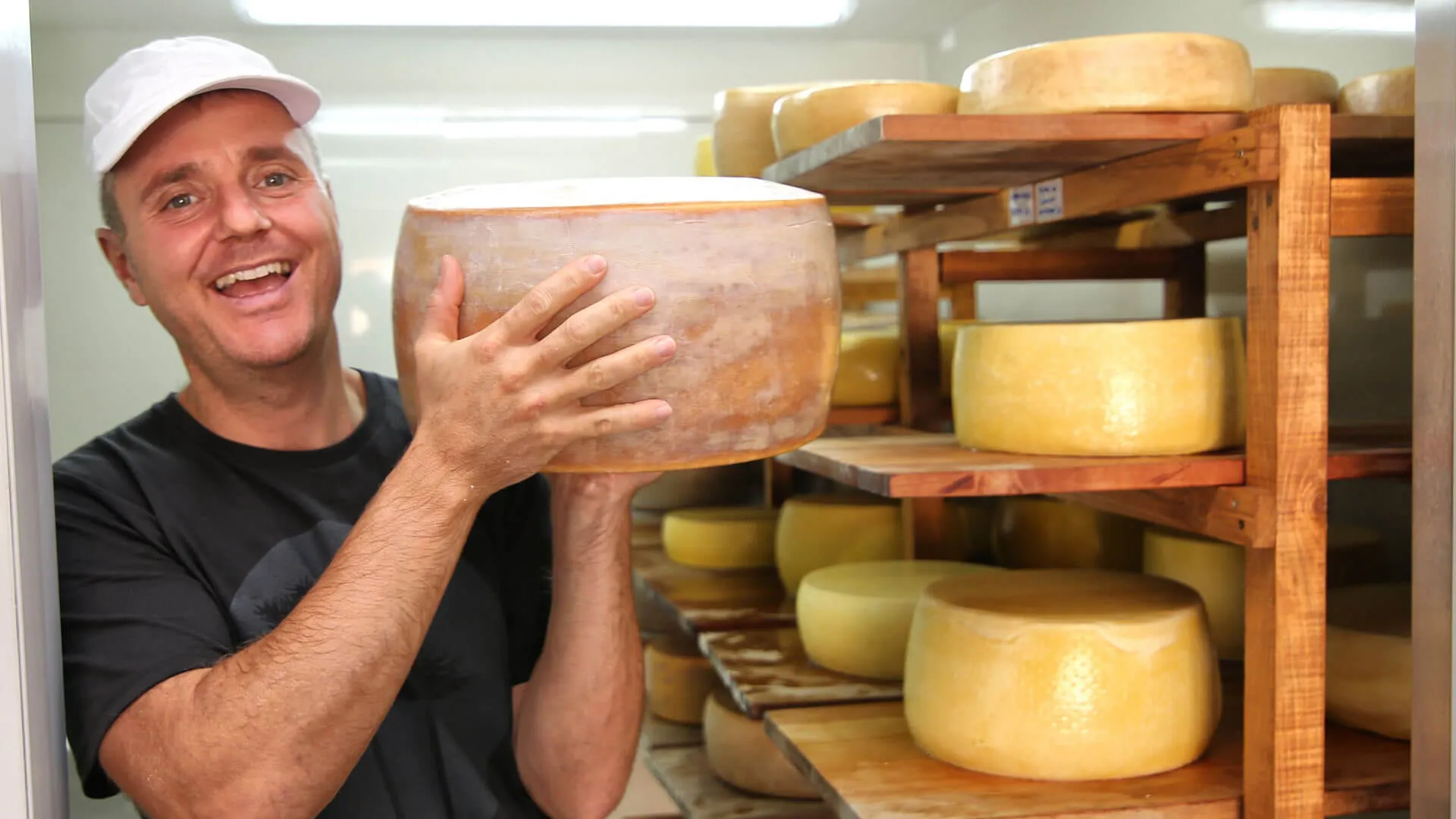 A man holds a wheel of cheese at the &Beyond Vira Vira cheese factory