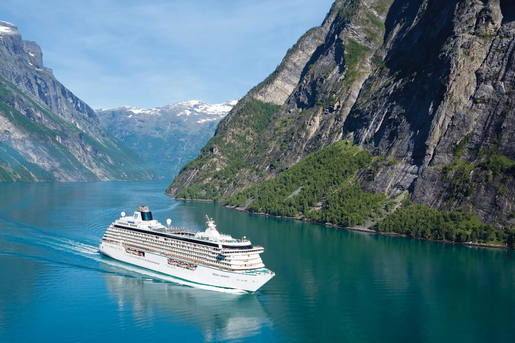 A Crystal Cruises ship sails through a channel surrounded by mountains
