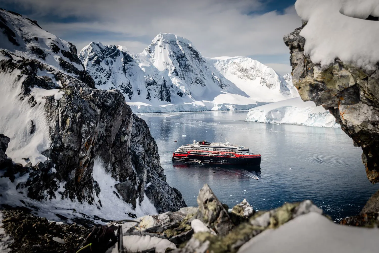 An HX Expeditions cruise ship between mountains in Antarctica