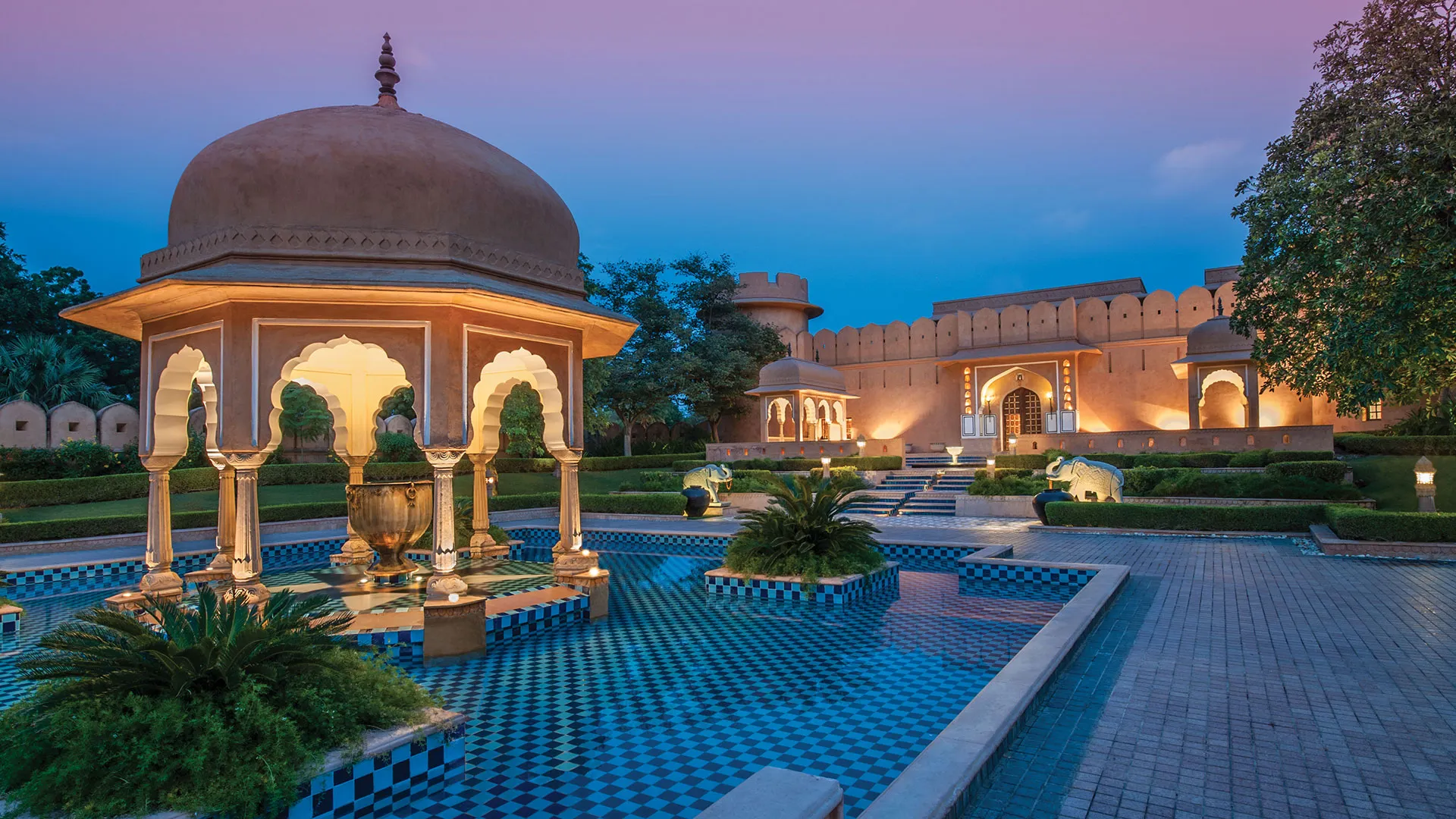 An Oberoi resort pool area at dusk