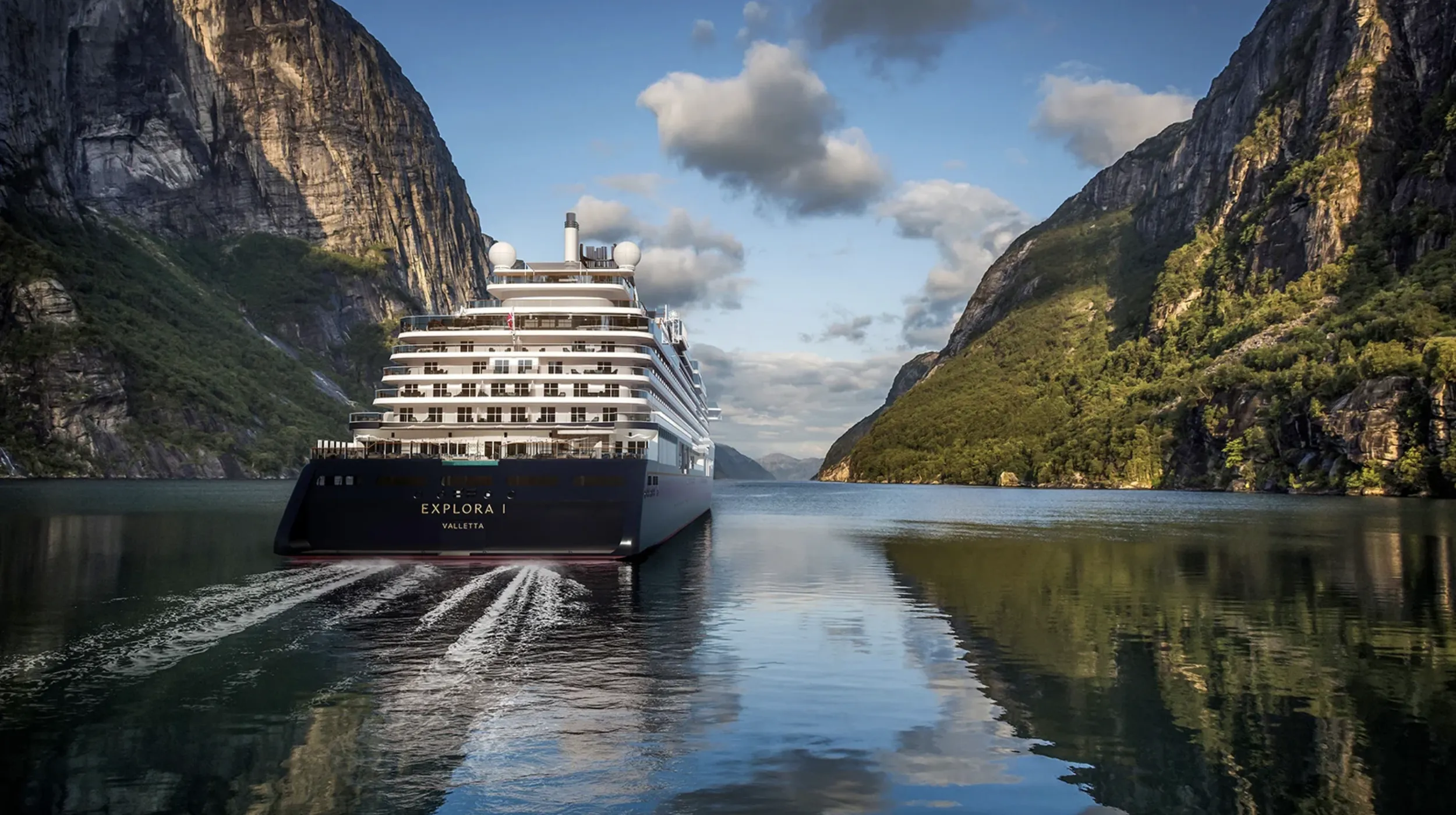 An Explora Journeys ship cruises through a fjord