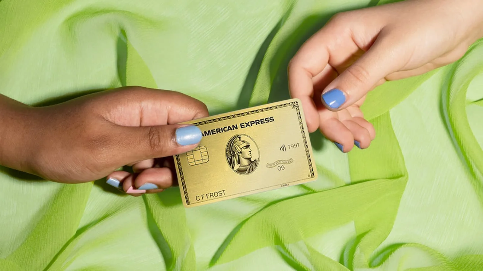 2 hands grabbing an American Express gold card