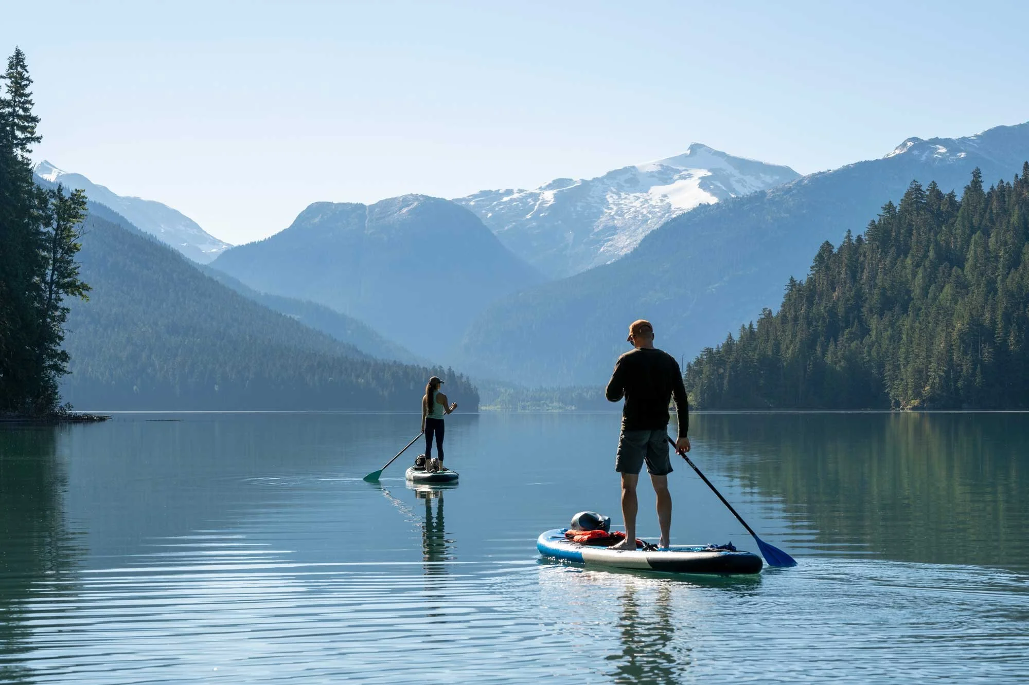 A couple paddle board on a lake in the mountains