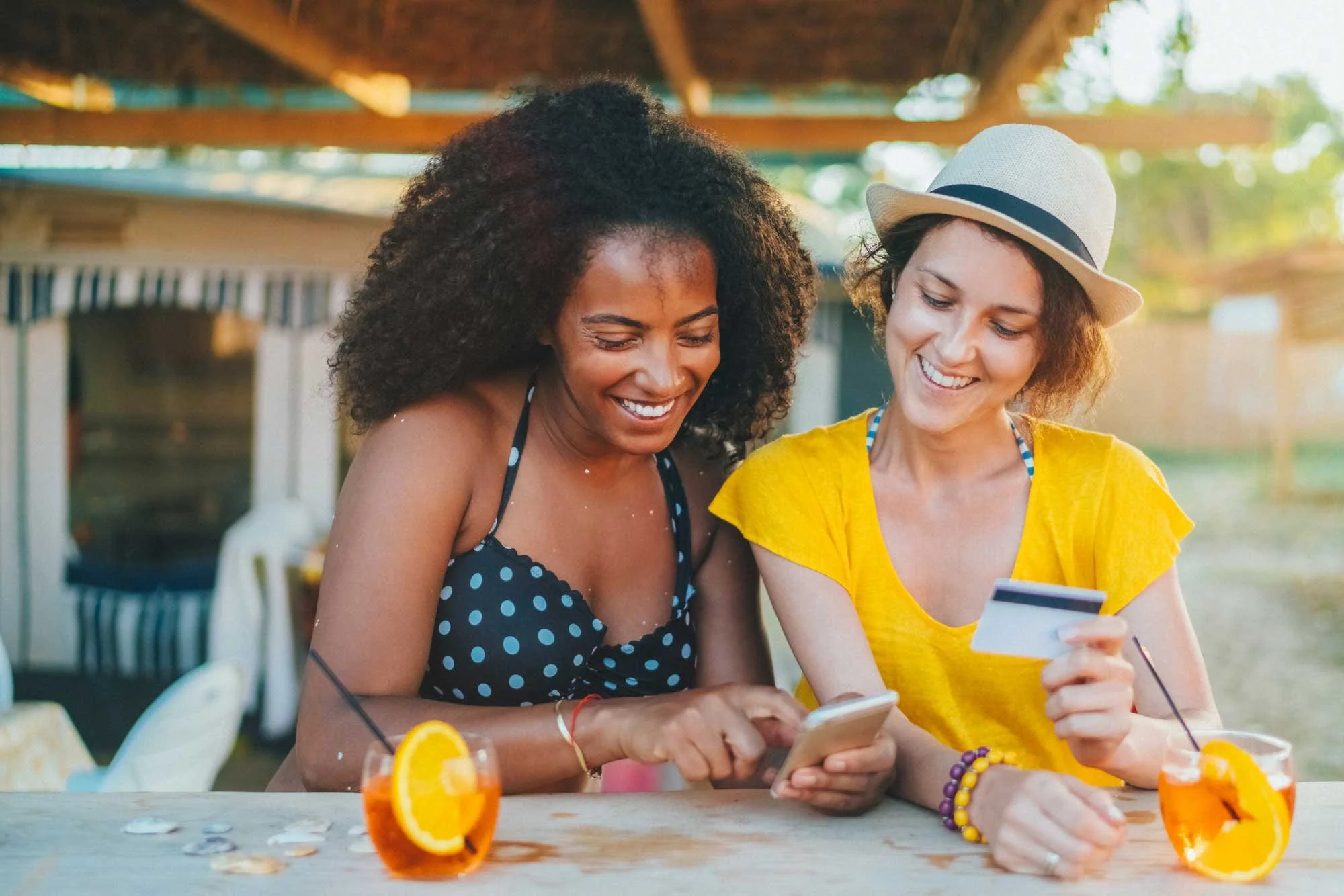 Two women using a credit card and mobile app at a restaurant