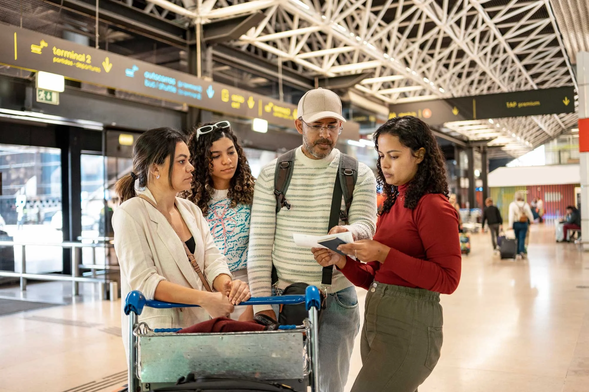 A family huddles together in an airport, looking nervous