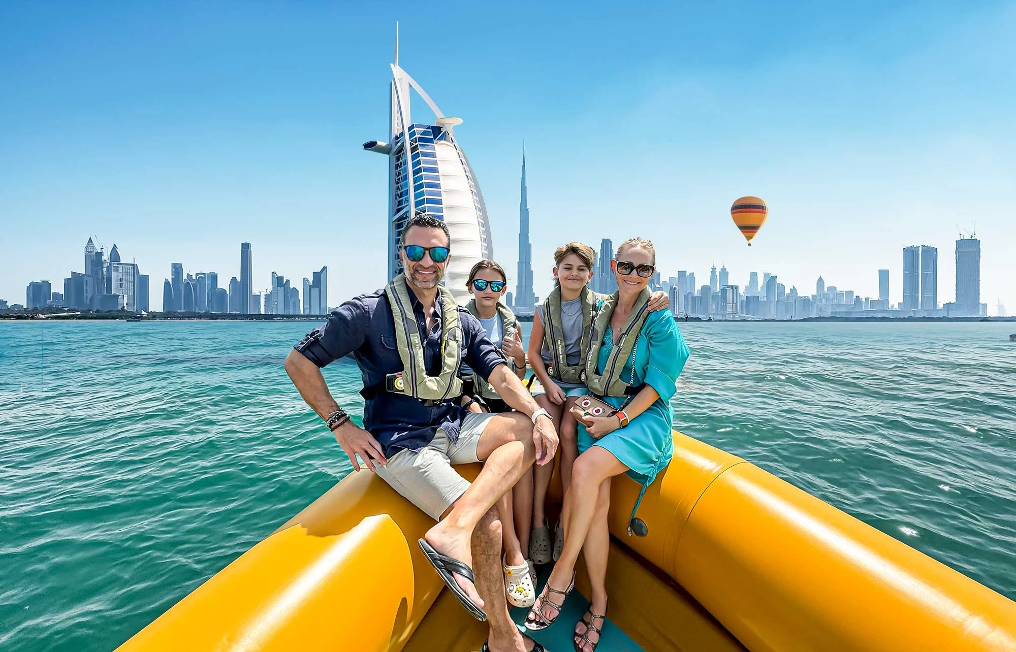 The Lockwood family sits on a small boat in front of the Dubai skyline