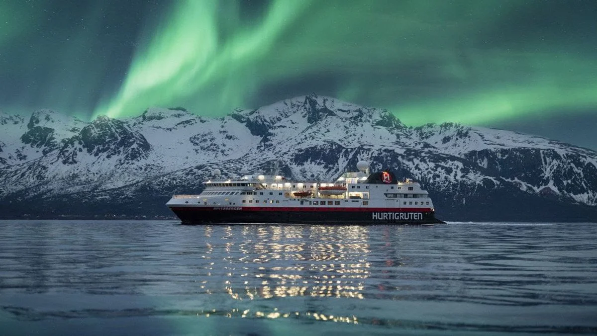 A Hurtigruten expedition ship sails past the norther lights