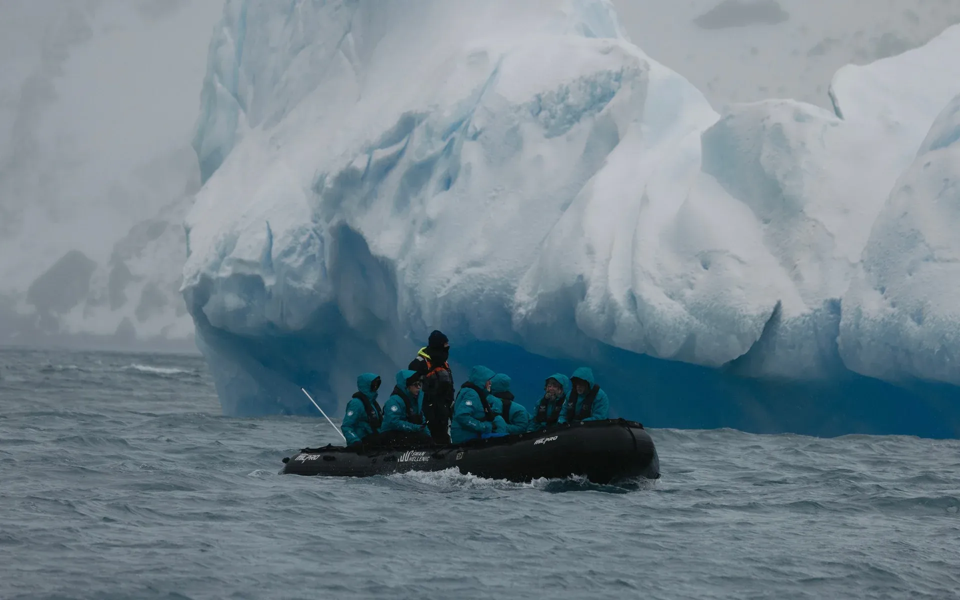 A zodiac cruises past an iceberg in Antarctica