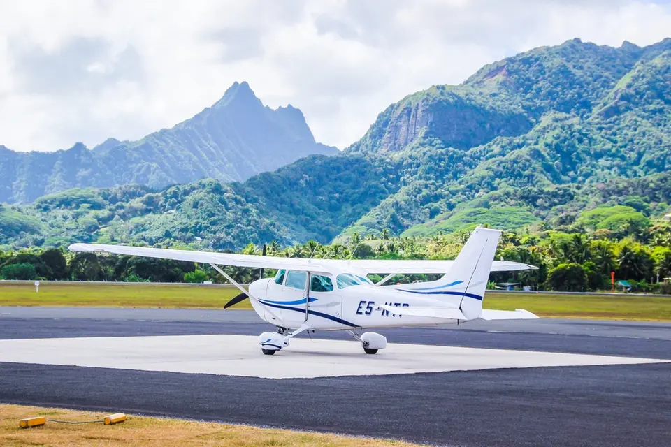 A Cessna taxis in Rarotonga with mountains in the background