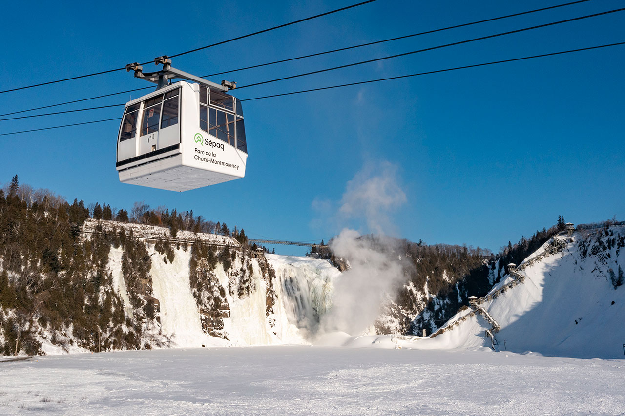 A gondola rides past a snowy Montmorency Falls