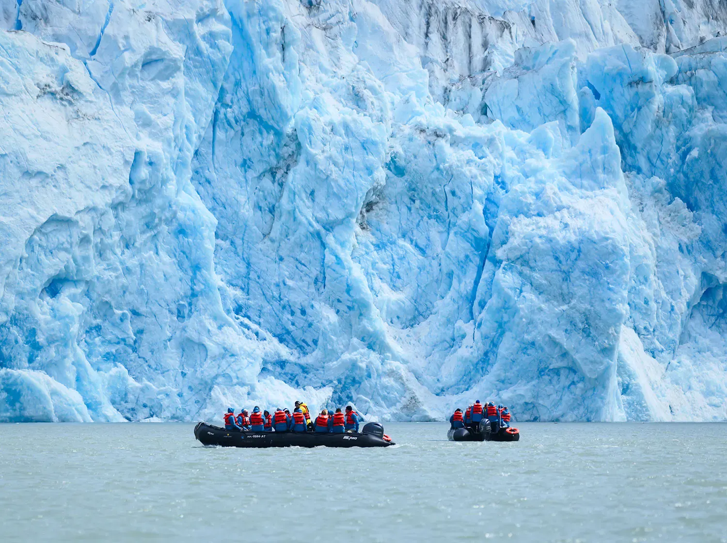 2 zodiacs cruise past a massive glacier in Alaska