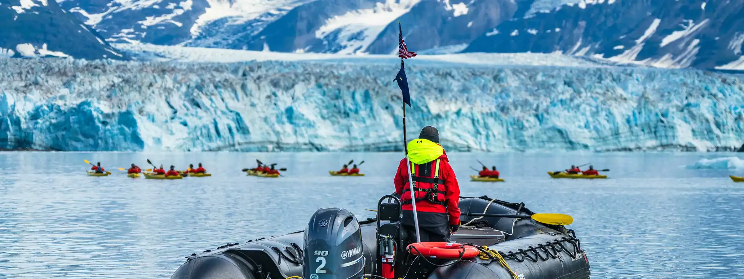 2 zodiacs cruise past a massive glacier in Alaska