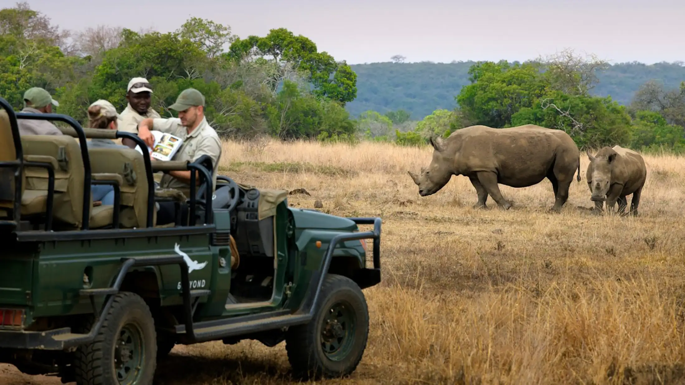 An &Beyond safari jeep next to rhinos