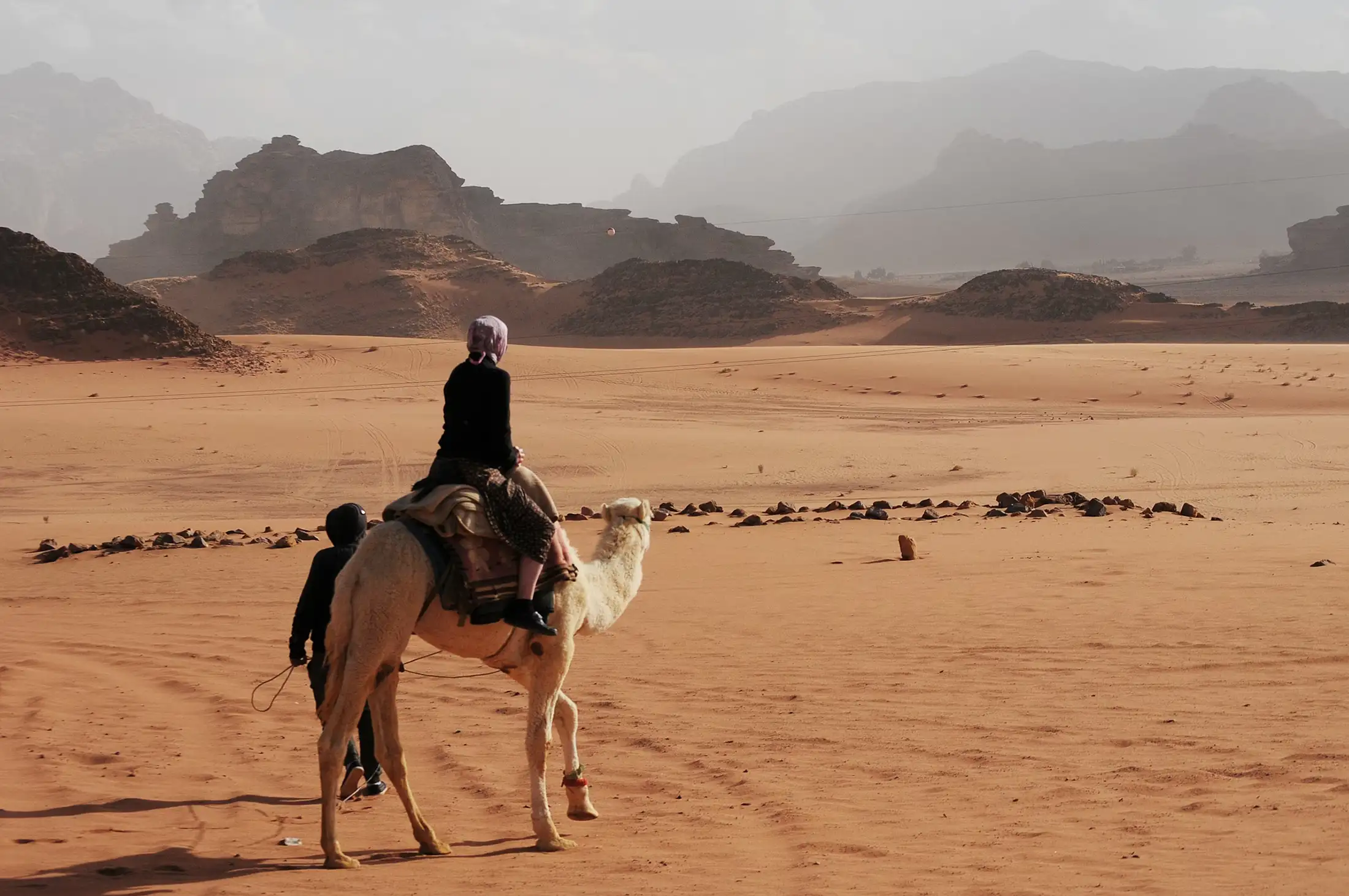 A man rides a camel in Wadi Rum, Jordan