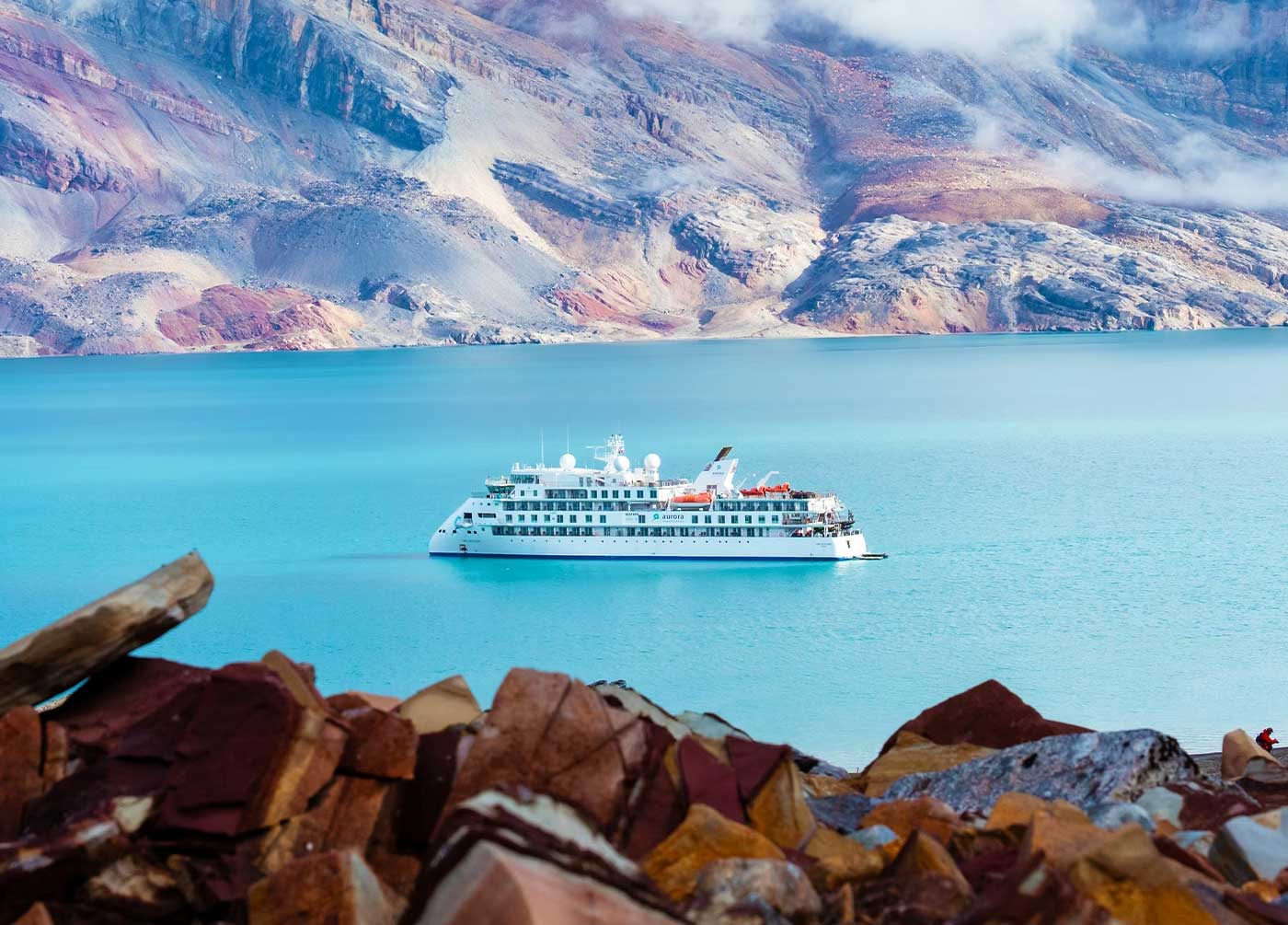 An Aurora Expeditions cruise ship sails through Gatorade-colored waters