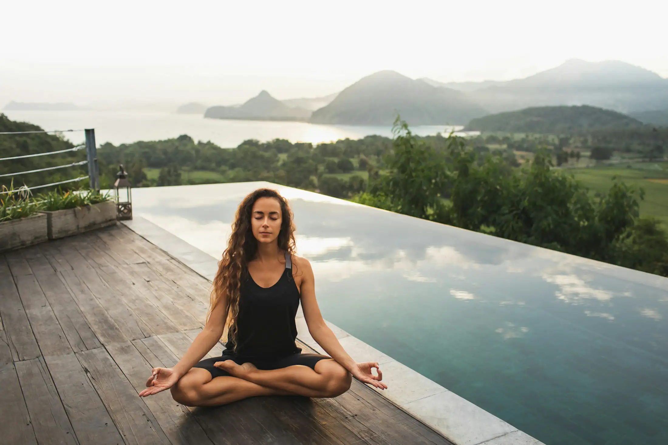 A woman practices yoga on the deck of her Asian resort