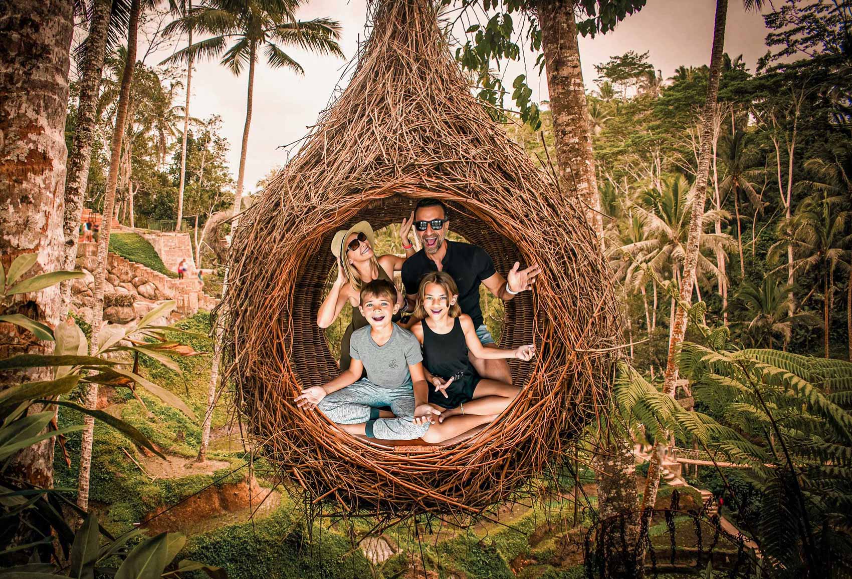 The Lockwood family sitting in a hanging nest at a Bali rice field