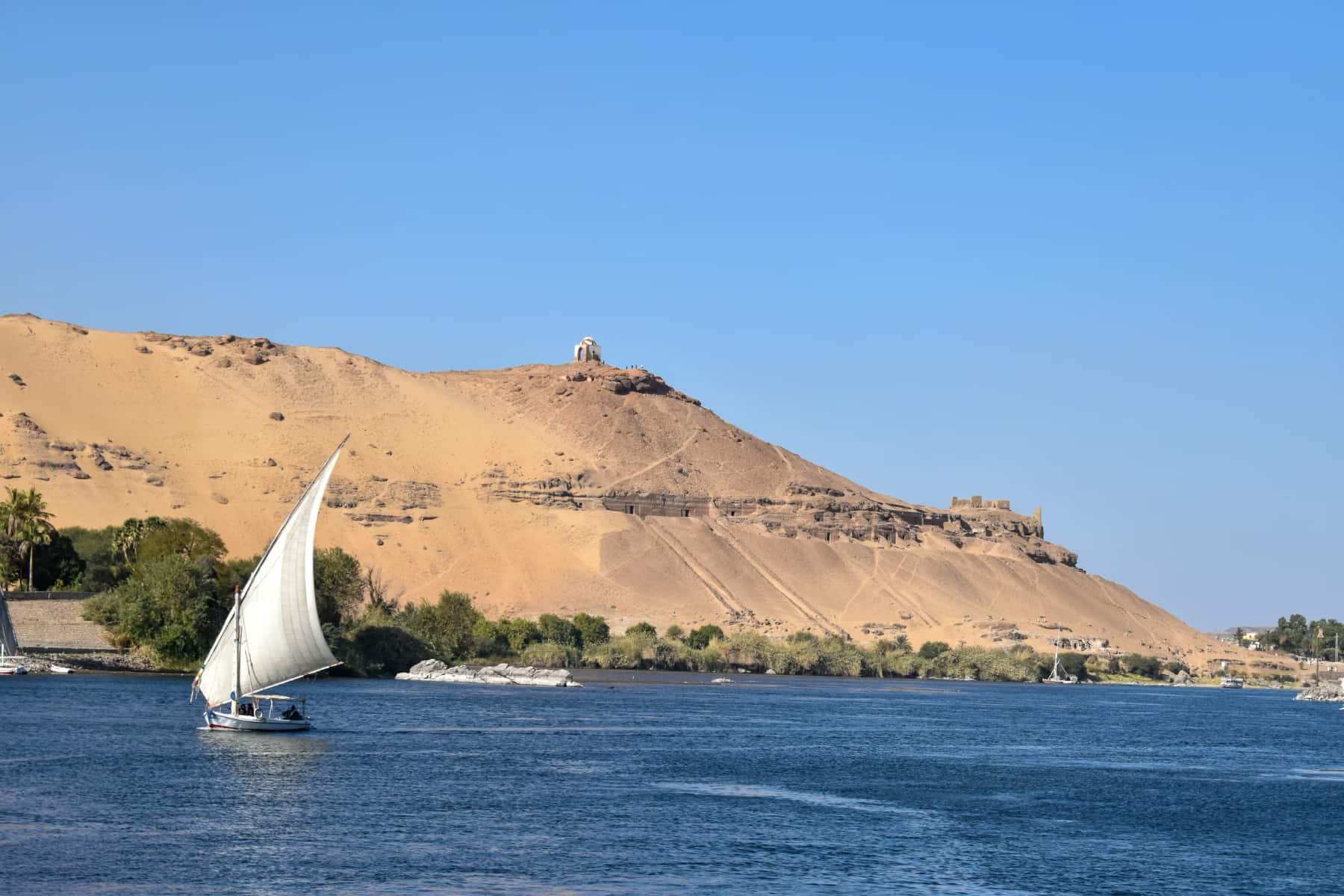 A lone sailboat cruises along the Nile River