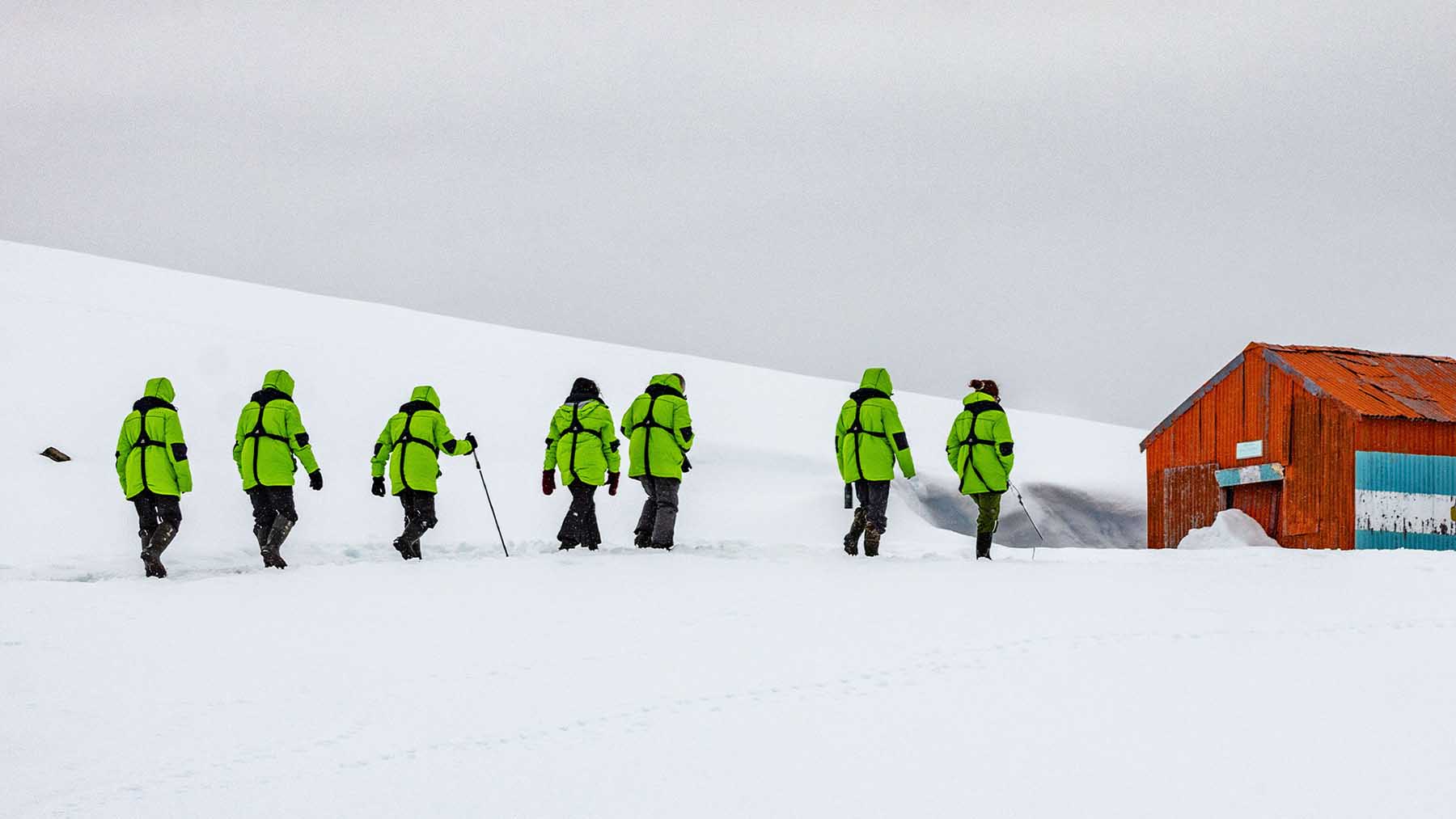 Hikers walk toward an orange building in Antarctica