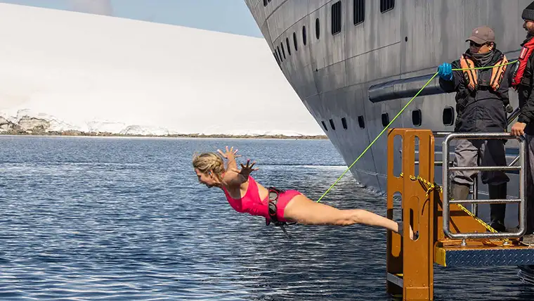 A woman takes the polar plunge off the Atlas World Navigator in Antarctica