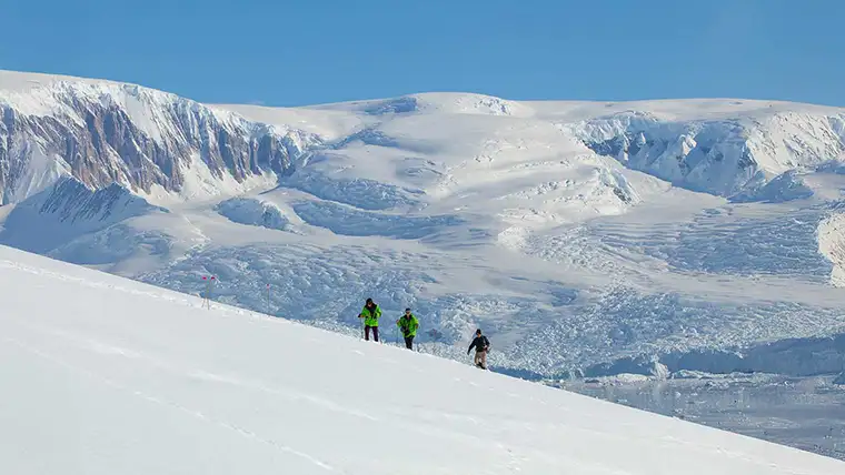 Hikers climbing a snowy hill in Antarctica