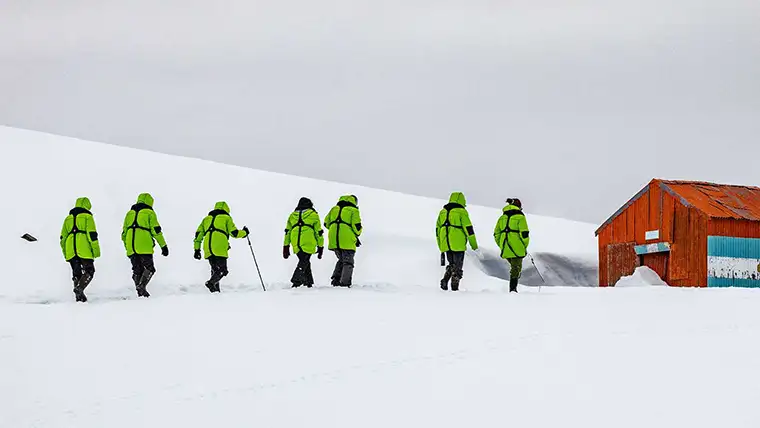 Hikers approach an outpost building in Antarctica