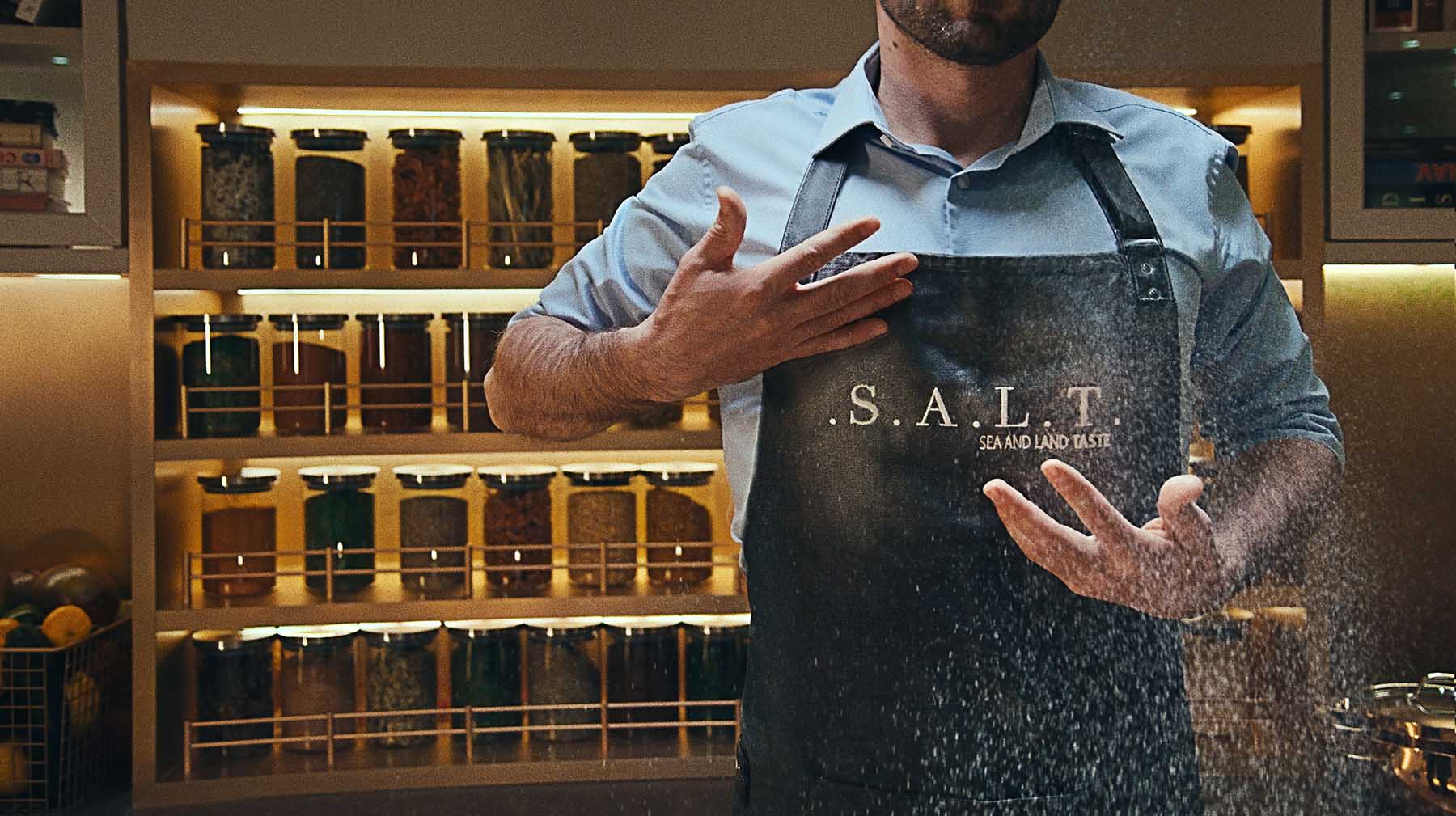 A man wearing a S.A.L.T. apron and baking with flour on a Silversea cruise ship