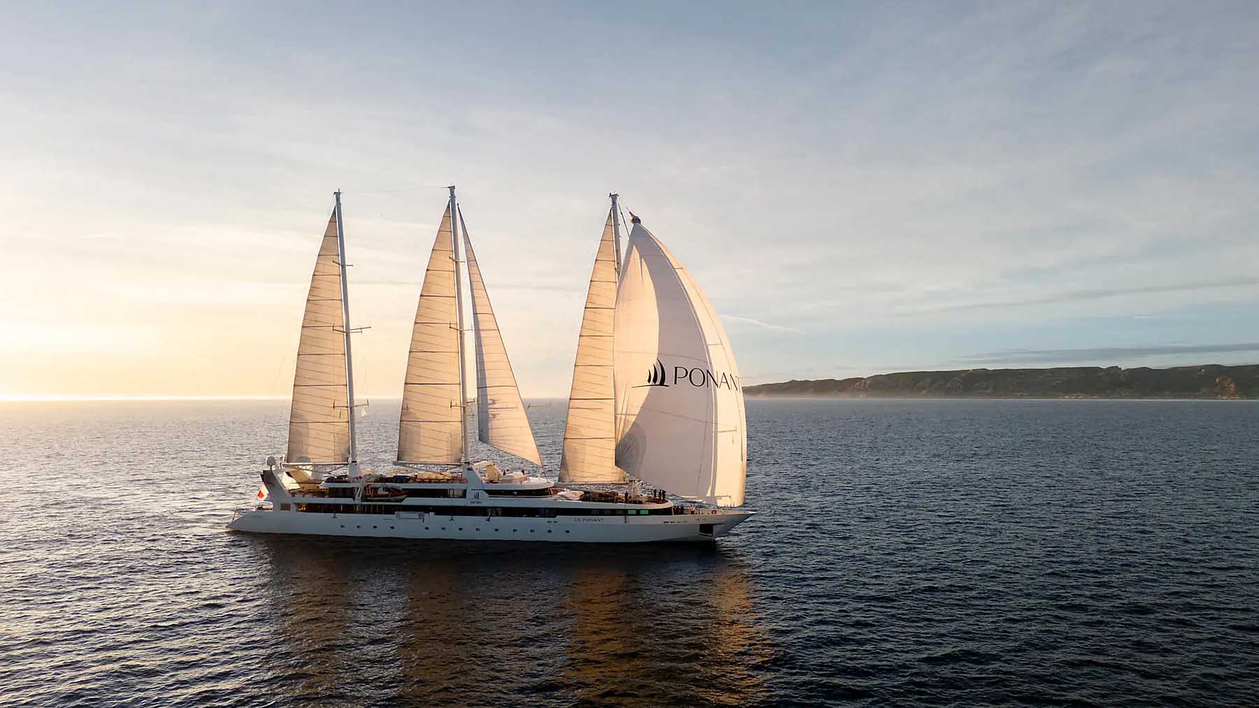 A Ponant sailboat cruise ship at sunset