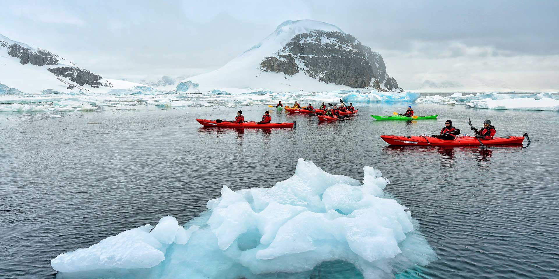 Red kayaks paddle through icy waters in Antarctica