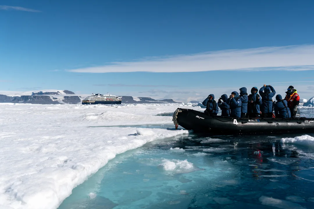 A zodiac lands on a snowy shore in Antarctica