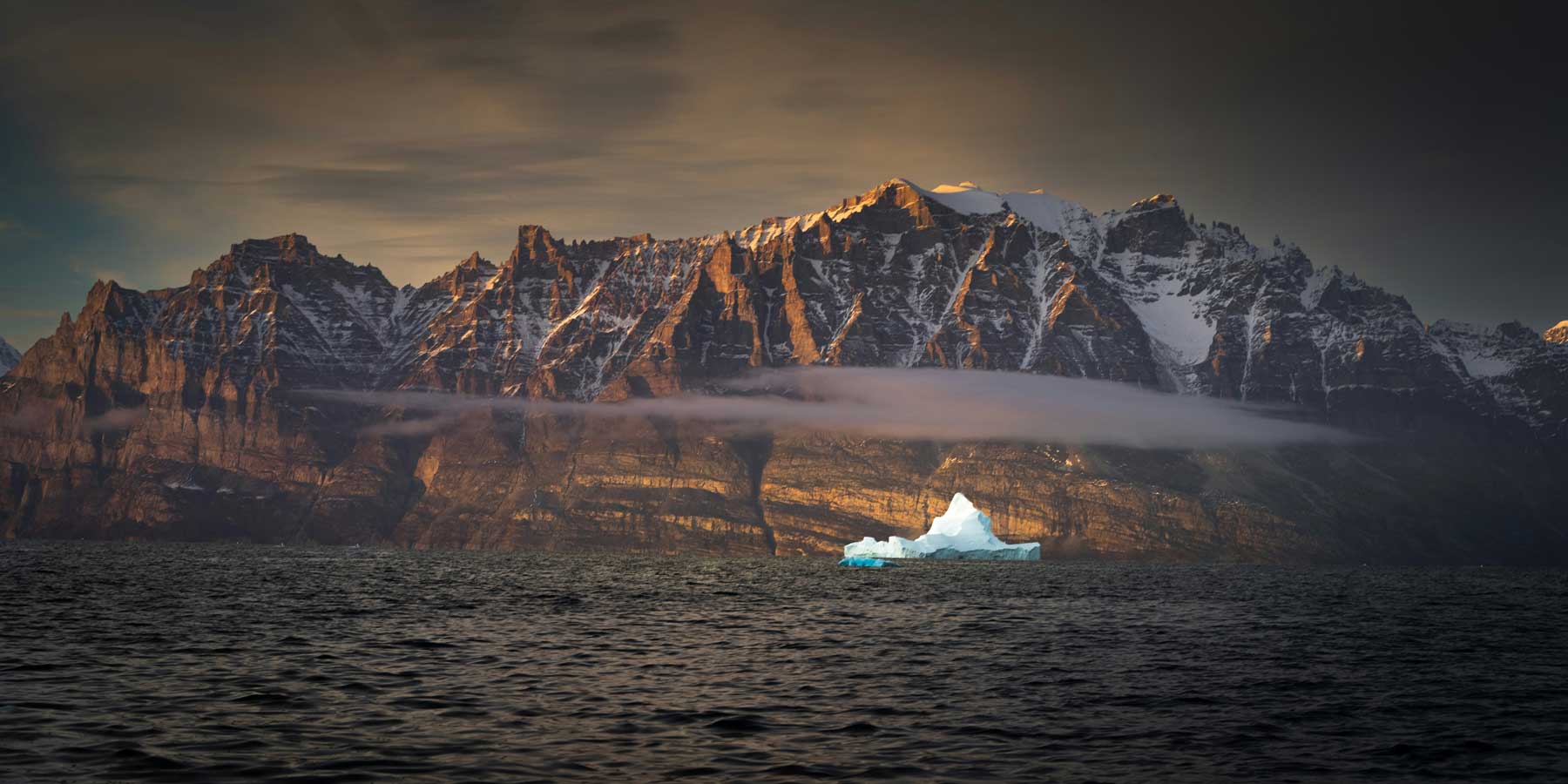 A sunset view of a mountainous coast in Greenland