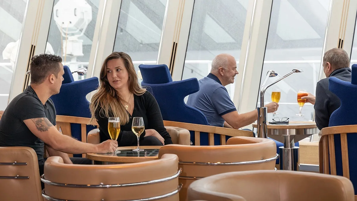 People have cocktails in the Explorer Lounge on an HX cruise ship
